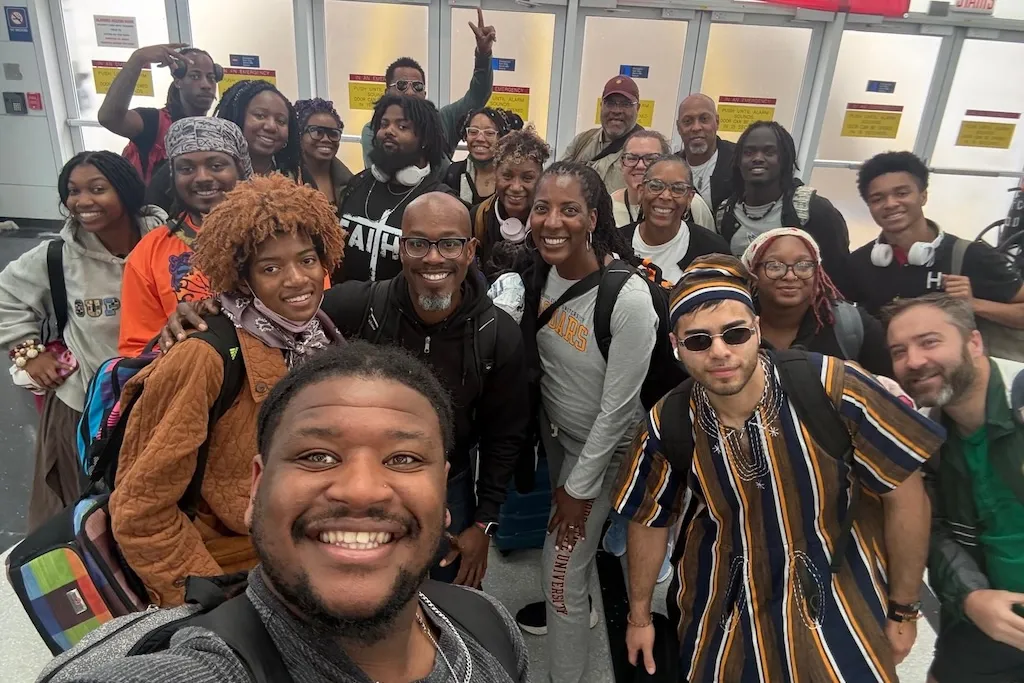 Smiling group of travelers taking a selfie in an airport terminal.
