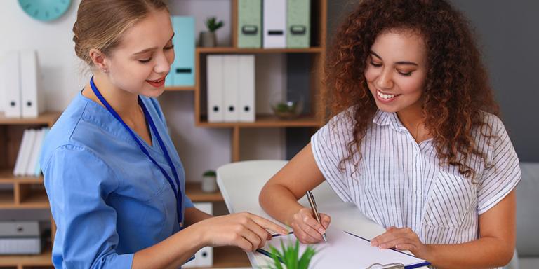 Medical Professional with patient filling out forms