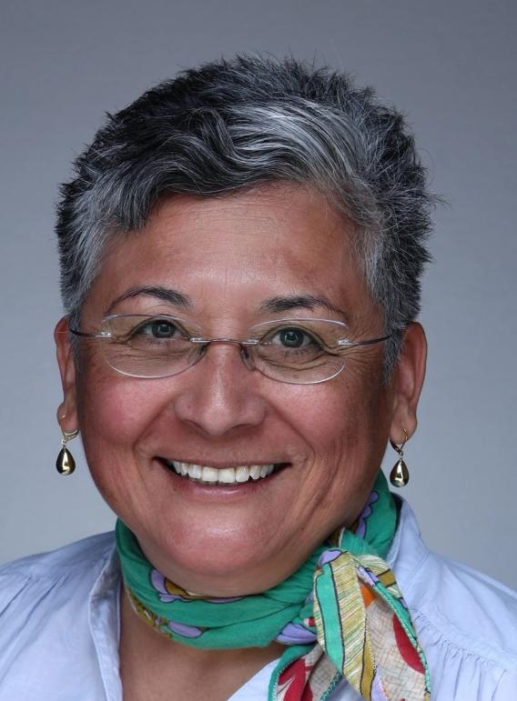 Woman with gray hair, glasses, and a green patterned scarf smiling.