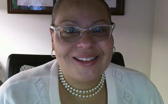 Photo of woman in glasses, dressed in a white sweater and pearl necklace